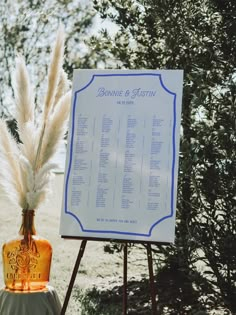 a wedding seating sign and vase with pamonini in it