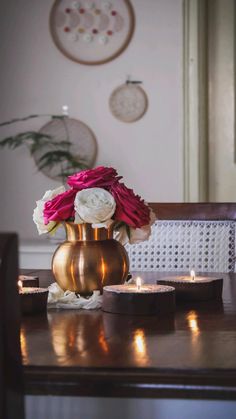 a vase filled with flowers sitting on top of a wooden table next to two candles