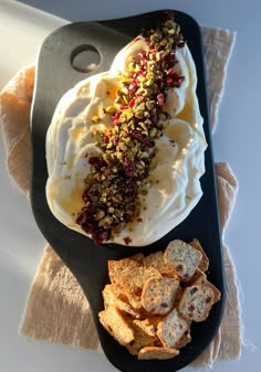 there is a spoon with some food on it next to crackers and bread chips