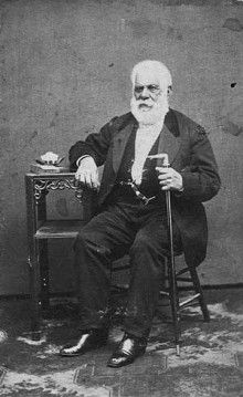 an old black and white photo of a man sitting in a chair with a cane