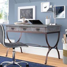 a desk with a laptop on it in front of a blue wall and wooden floors