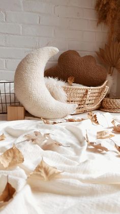 two stuffed animals in a basket on top of a white blanket next to a brick wall