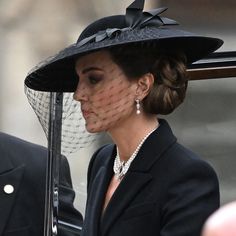 a woman wearing a hat and holding a cane in front of her face while standing next to another man