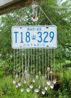 a blue and white license plate hanging from a chain with lots of glass beads attached to it