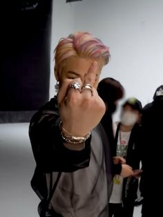 a man with pink hair and piercings making a hand gesture