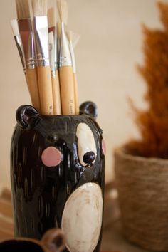 there is a bear shaped vase with paint brushes in it