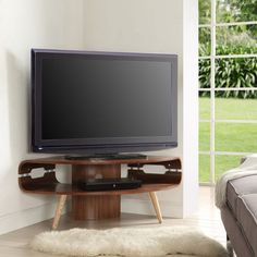 a flat screen tv sitting on top of a wooden stand in front of a window