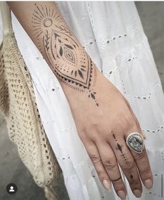 a woman's hand with a tattoo on it and a ring in the middle