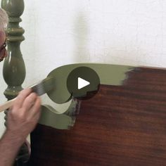 a man is painting a wooden headboard with green paint