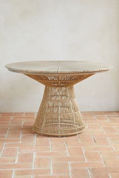 a wicker table sitting on top of a brick floor next to a white wall