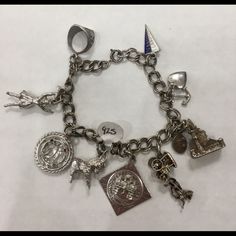 925 Sterling Silver Charm Bracelet W/ Castle, Anchor, Horse And Carriage Featured Charms: "Pennbrook" Blue And White Flag, Heart And Anchor, Castle, Horse And Carriage, "Merry Christmas", Donkey, 16 B-Day W/Blue And Red Gems", Cheerleader, Military Ring Very Good Condition: W/Slight Tarnish Size: 6.00" Material: Sterling Silver Blue And White Flag, Red Gems, Christmas Donkey, Horse And Carriage, White Flag, Sterling Silver Charm Bracelet, Silver Charm Bracelet, B Day, Sterling Silver Charm