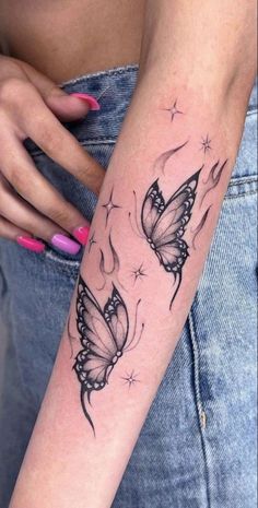 a woman's arm with two butterflies on it and stars in the sky above