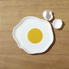 an egg and two eggshells on a wooden table with one broken in half