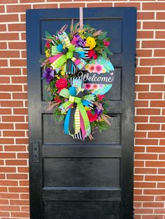 a black door with a welcome wreath on it