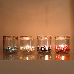 four jars filled with candles sitting on top of a counter