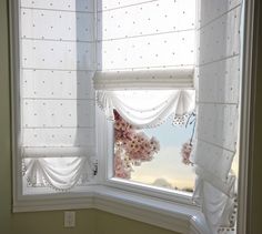 a bathroom window with white curtains and pink flowers