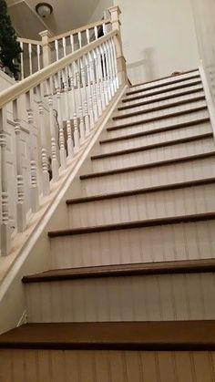 there is a stair case on the side of this house that has white railings and wood handrails