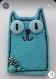 a blue cat brooch with eyes and beads on it