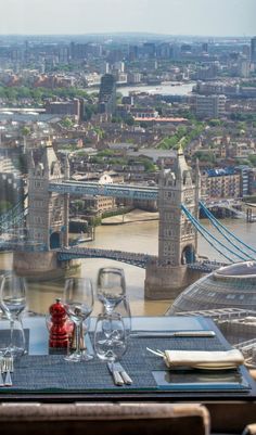 the table is set with wine glasses and place settings in front of an aerial view of london