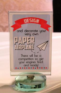 there is a sign that says design and decorate your very own paper airplane here will be a competition so get your engines ready