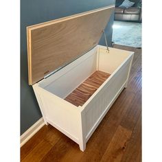 an open white box with wood in it on a wooden floor next to a blue wall