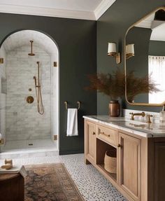 a bathroom with green walls and white tile on the floor, along with gold fixtures