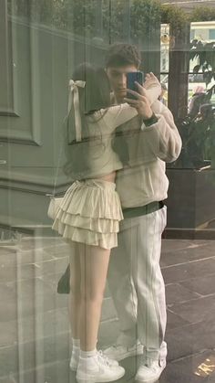 a man and woman taking a selfie in front of a store window with their cell phones