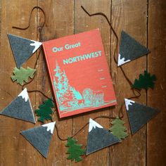 a book sitting on top of a wooden table next to some cut out trees and leaves