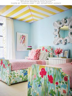 two beds in a room with colorful decor on the walls and ceiling, along with striped drapes