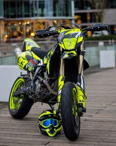 a yellow and black motorcycle parked on top of a wooden floor next to a building