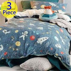 a bed with space themed comforters and pillows on top of it, next to a night stand