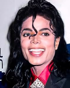 a close up of a person wearing a suit and tie with long black hair smiling at the camera