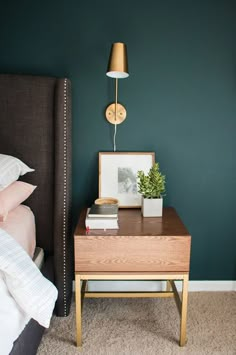 a bedroom with a bed, nightstand and night stand on carpeted floor next to green wall