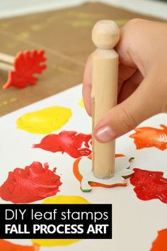 a person is stamping out fall leaves on a piece of paper with a wooden stick