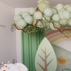 a green vase filled with white balls and flowers next to a wall mural in a room