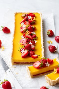 two slices of lemon tart with strawberries on top and one slice cut in half