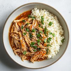 a bowl filled with rice and meat covered in sauce