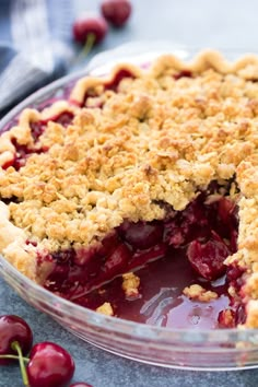 a pie that has been cut into pieces and is sitting on a table next to some cherries