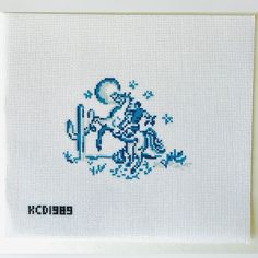 a cross - stitch picture of a cowboy riding a horse with cactuses in the background