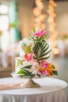 a wedding cake decorated with tropical flowers and greenery