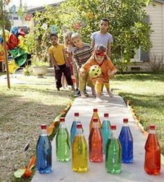 children are playing with water bottles on a table in front of a house that is decorated with balloons and streamers