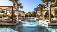 an outdoor swimming pool with cabanas and lounge chairs