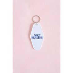 a keychain with the words deep breaths on it hanging from a pink wall