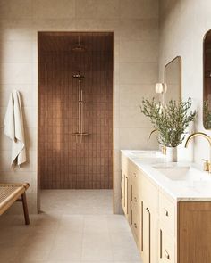 a bathroom with two sinks and a wooden bench in front of the shower area is shown