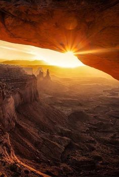 the sun is setting over canyons and cliffs in this desert landscape, as seen from inside a cave