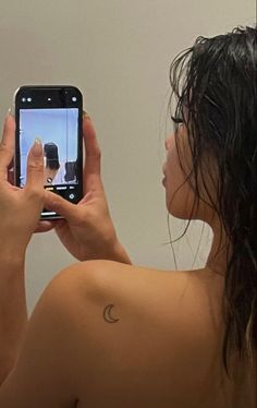 a woman taking a selfie with her cell phone in front of her back shoulder