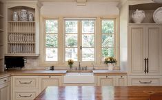 a kitchen with white cabinets and wooden counter tops next to a window that has glass panes on it