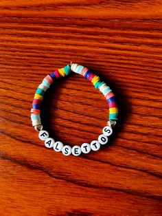 a beaded bracelet with the word boston written in white beads on a wooden surface