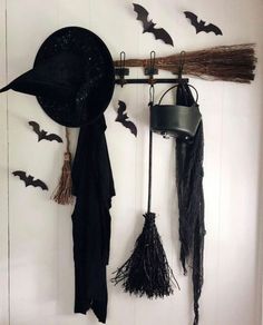 bats and brooms are hanging on the wall next to a bucket with witch's hat