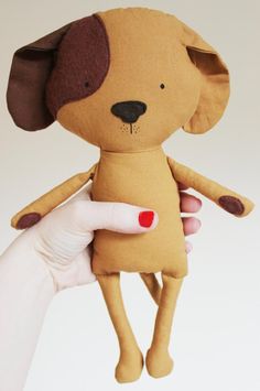 a hand holding a stuffed dog toy in it's right hand and the other hand is pointing at it